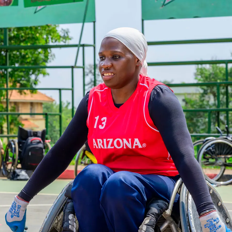 Woman wheelchair rugby athlete wearing a red Uganda team bib