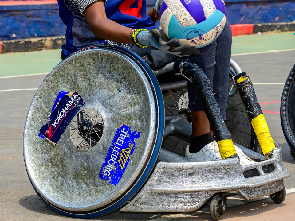 Woman athlete controlling a rugby ball in her sports wheelchair